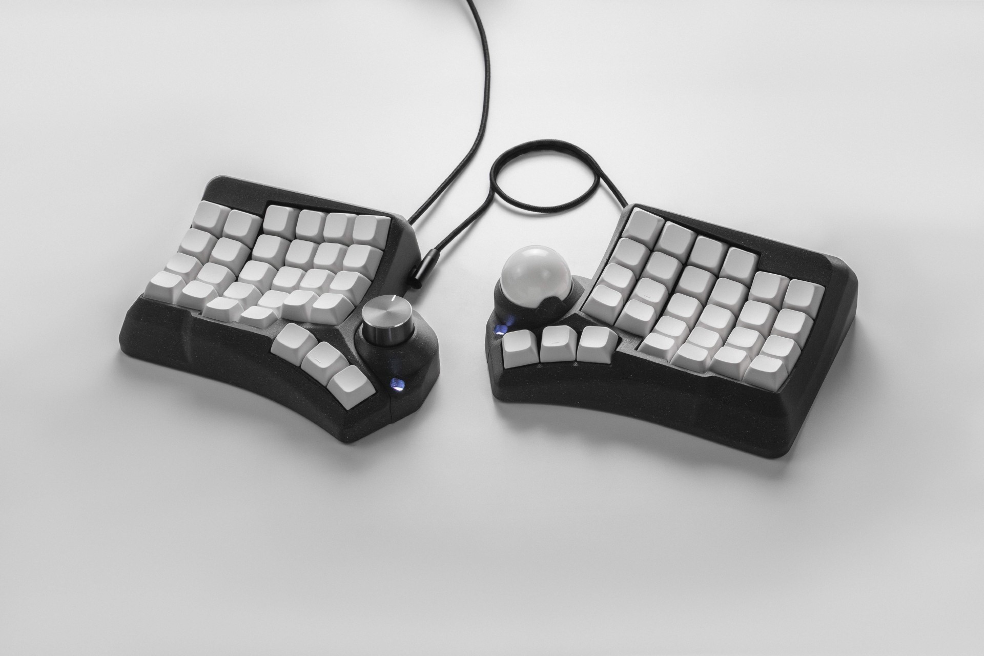 Black Phenom split ergonomic keyboard with white keycaps, rotary encoder, and trackball