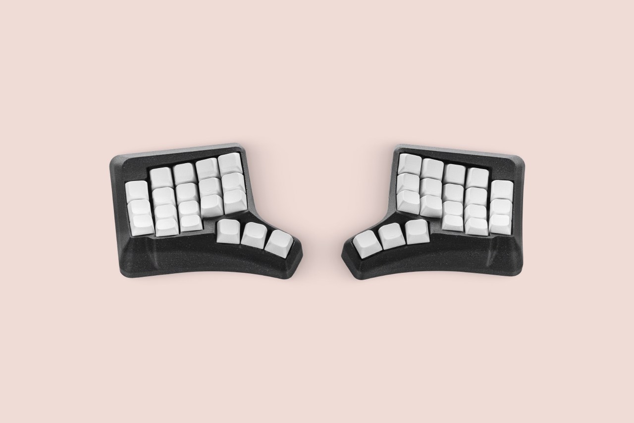 Phenom Micro compact split ergonomic keyboard with white keycaps in a black sculpted case
