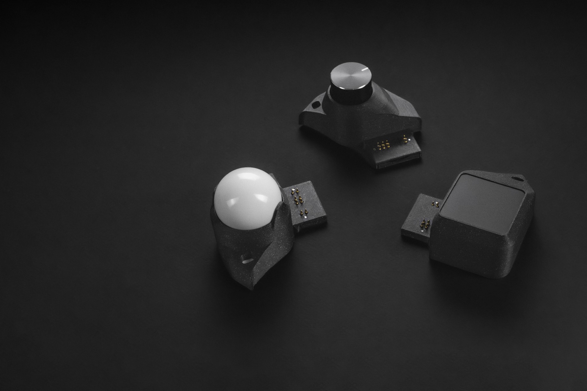 Trackball, encoder, and touchpad control modules arranged on a dark surface