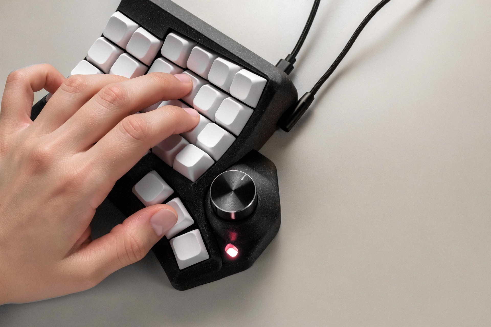 Hand resting naturally across the sculpted Phenom keywell beside the encoder module